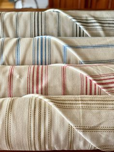 four different colored striped bedspreads on a wooden bed with a headboard in the background