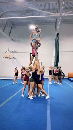 a group of young women standing on top of each other in front of a gym floor