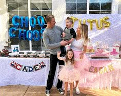 a man, woman and child standing in front of a cake table