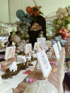 a table topped with lots of white plates covered in frosting and decorations under a tent