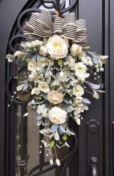 a bouquet of flowers hanging from the front door of a house with a bow on it