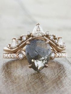 an engagement ring with a pear shaped blue diamond surrounded by white and brown diamonds, on top of a wooden surface