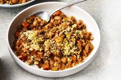 two bowls filled with food sitting on top of a table next to a spoon and fork