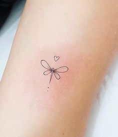 a small dragonfly tattoo on the arm with hearts around it's wings and tail