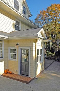 a small house with a porch and two pumpkins sitting on the front door steps