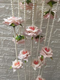 some pink flowers and pearls are hanging from the ceiling