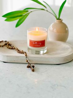 a candle on a tray next to a plant