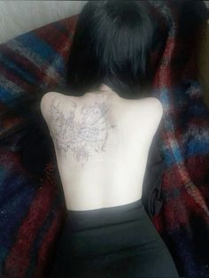 the back of a woman's body with tattoos on her upper and lower back