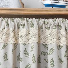 a sailboat is in the background behind a window curtain with lace on it's valance