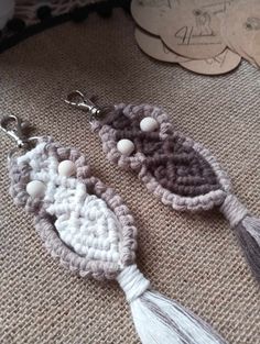 two crocheted earrings with tassels and beads on top of a table