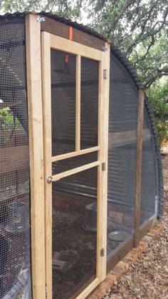 an outdoor chicken coop is shown with the door open and mesh covering over it's sides