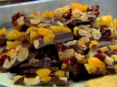 a pile of fruit and nuts sitting on top of a white plate next to crackers