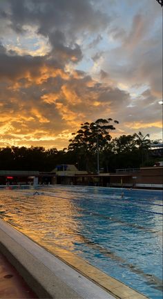 the sun is setting over an outdoor swimming pool