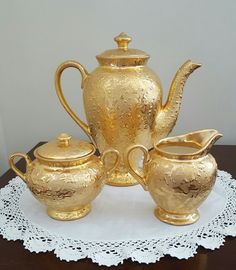 a gold tea set sitting on top of a table next to a white doily