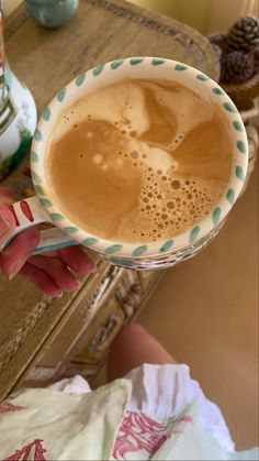 a person holding a cup of coffee on top of a table