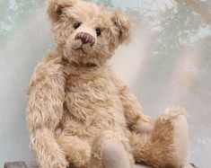 a brown teddy bear sitting on top of a wooden table next to a forest background