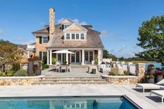 a large house with a pool in front of it and an outdoor dining area on the other side