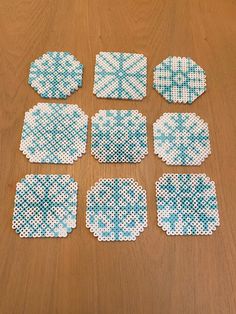 six pieces of blue and white cross stitched coasters on a wooden table top