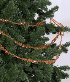 a close up of a christmas tree with some lights on it's branches and chains hanging from the top