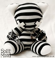 a black and white striped teddy bear with beads on it's neck, sitting in front of a white background