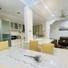 a white table with yellow chairs in a living room next to a kitchen and dining area