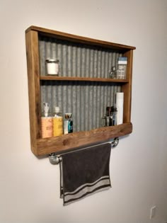 a wooden shelf with towels hanging from it's sides and some bottles on top