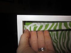 a woman's hand is holding onto a green and white striped curtain in the dark