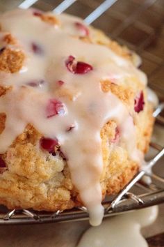 a muffin with icing and cranberries on a cooling rack, ready to be eaten