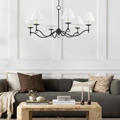 a living room with a couch, coffee table and chandelier hanging from the ceiling