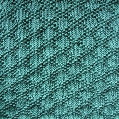 a green knitted blanket is shown in close up, with small squares on it