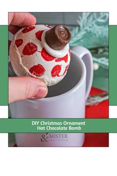 someone is holding a christmas ornament in a mug with hot chocolate on top