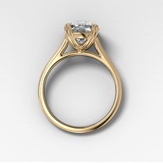 a yellow gold engagement ring with an oval cut diamond in the center, on a white background