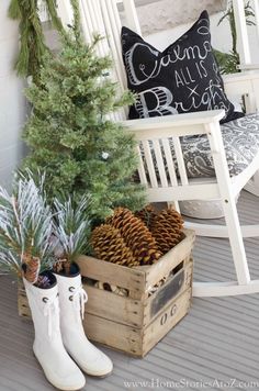 a white rocking chair sitting on top of a porch next to a christmas tree