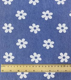 a ruler is next to a blue fabric with white flowers on it