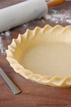 an uncooked pie crust sits on a table next to a rolling dough roller