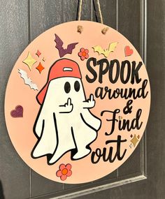 a wooden sign that says spook around and find out with a ghost on it