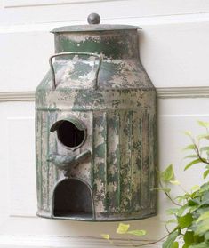 an old green metal birdhouse hanging on the side of a white door next to a potted plant