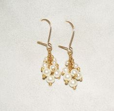 "A beautiful cluster pearl dangle earrings. These delicate dangle bridal earrings are both a timeless classic and modern Boho-chic. The earrings are made from cream Swarovski pearls with a hanging hook earring, The beads are connected loosely and individually, in a delicate cluster beadwork that allows them to move, and grants them a grape line look. This design is available with a hook or with a post - the hook can be replaced with a stud pearl earrings. These vintage-inspired earrings are made White Pearl Drop Cluster Earrings For Anniversary, White Pearl Drop Dangle Cluster Earrings, White Pearl Drop Cluster Earrings, Pearl Drop Cluster Earrings For Anniversary, Dangle Pearl Drop Cluster Earrings, Anniversary Pearl Drop Cluster Earrings, Gold Earrings Long, Stud Pearl Earrings, Dangle Pearl Earrings