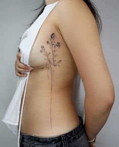 a woman with a flower tattoo on her back is looking at the camera and has one arm behind her back