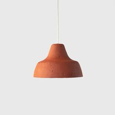 an orange pendant light hanging from a white ceiling