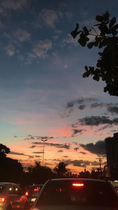 cars are parked on the side of the road as the sun sets in the distance