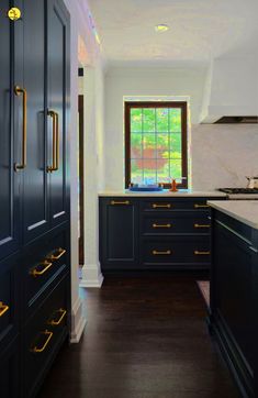 a kitchen with black cabinets and gold handles on the doors, along with white walls