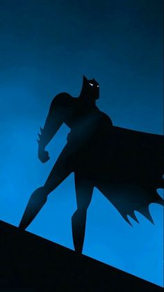 the shadow of a batman standing on top of a hill in front of a blue sky