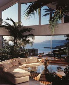 a living room filled with lots of furniture and large windows overlooking the ocean in front of it