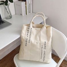 a white bag sitting on top of a chair next to a desk with a laptop