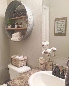 a white toilet sitting next to a bathroom sink under a metal shelf filled with towels