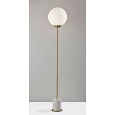 a floor lamp with a marble base and a white ball light on it's side