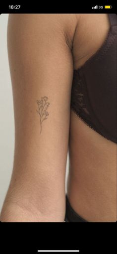 a woman's stomach with a small flower tattoo on her left side ribcage