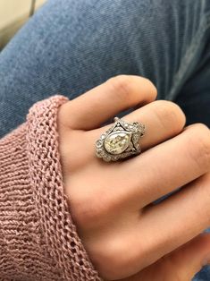 a woman's hand wearing a ring with an old - fashioned watch on it