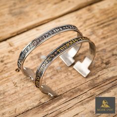 two silver bracelets sitting on top of a wooden table